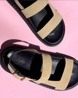 Black and beige sandals with 'Aloha' brand name on a pink background