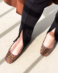 Person wearing leopard print flats on a light surface