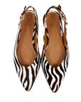 Pair of zebra print shoes with brown soles on a white background