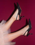 Black high-heeled shoes worn with a light pink tulle skirt against a red background
