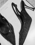 Black high-heeled shoes with lace design on an open book