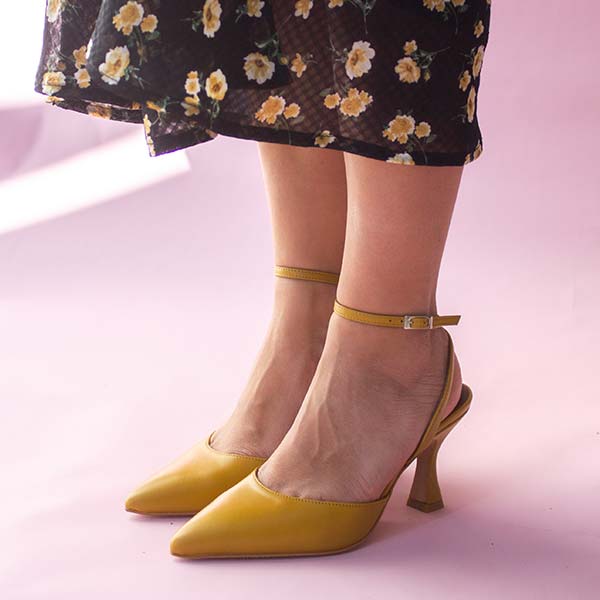 Alohas Cinderella marigold leather pumps on model wearing black and yellow floral skirt