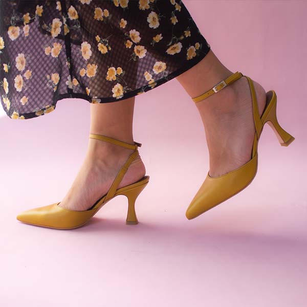 Alohas Cinderella marigold leather pumps on model wearing black and yellow floral skirt