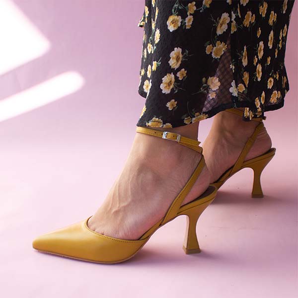 Alohas Cinderella marigold leather pumps on model wearing black and yellow floral skirt