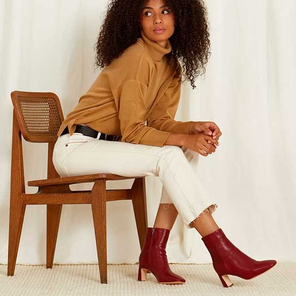 Mi/Mai Darcy mid heel ankle boot in red leather on model sitting on wooden chair