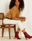 Mi/Mai Darcy mid heel ankle boot in red leather on model sitting on wooden chair 