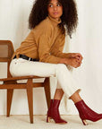 Mi/Mai Darcy mid heel ankle boot in red leather on model sitting on wooden chair