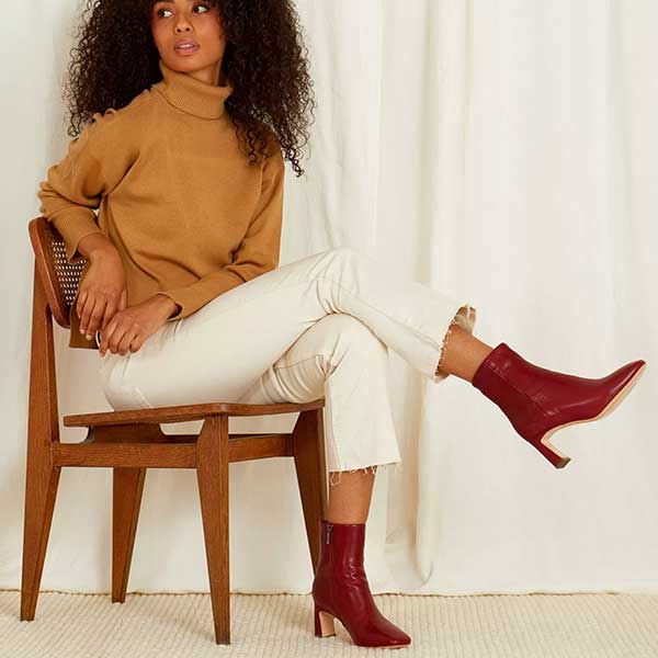 Mi/Mai Darcy mid heel ankle boot in red leather on model sitting on wooden chair