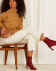 Mi/Mai Darcy mid heel ankle boot in red leather on model sitting on wooden chair