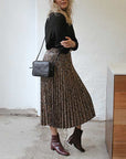model wearing black knit, snakeprint pleated skirt, black crossbody bag and Mint&Rose sol wine leather ankle boot 