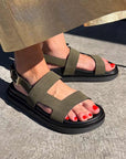 khaki sandals with black soles worn on a concrete surface