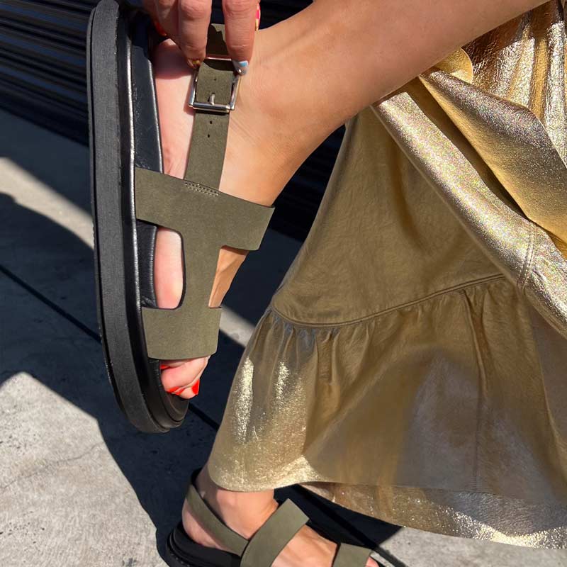 Person wearing khaki green sandals with a gold glittery dress.