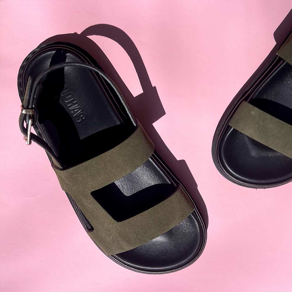 Black and khaki sandals on a pink background