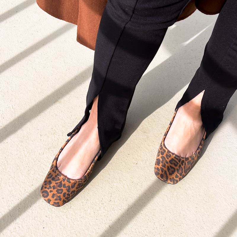 Person wearing leopard print flats on a light surface