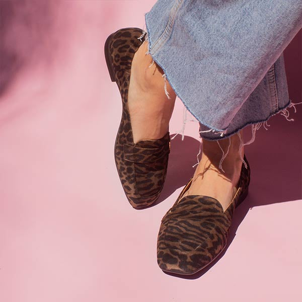 model in denim jeans and brown leopard print suede loafers in front of pink backdrop