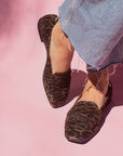 model in denim jeans and brown leopard print suede loafers in front of pink backdrop