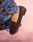 model in blue and brown printed satin pants and brown leopard print suede loafers in front of pink backdrop