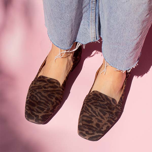 model in denim jeans and brown leopard print suede loafers in front of pink backdrop