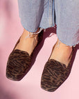 model in denim jeans and brown leopard print suede loafers in front of pink backdrop