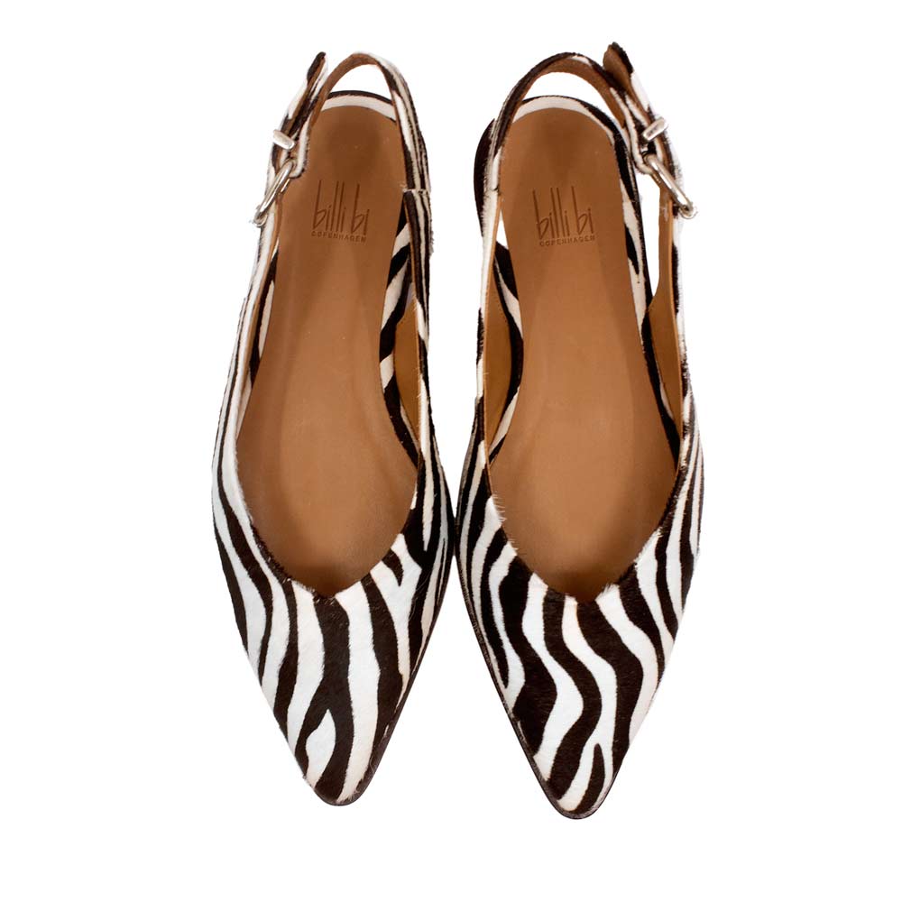 Pair of zebra print shoes with brown soles on a white background