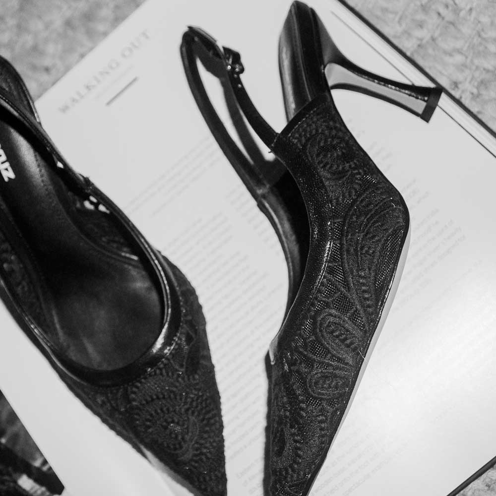 Black high-heeled shoes with lace design on an open book