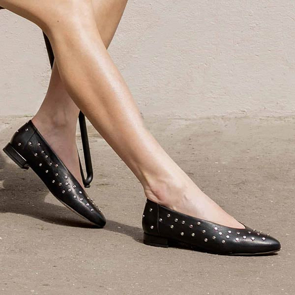 model wearing black leather ballet flats with silver studs from knee down