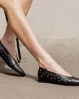 model wearing black leather ballet flats with silver studs from knee down