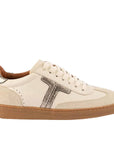 Cream suede and leather sneaker with metallic accents and a gum sole on a white background