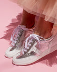 model wearing peach tulle skirt and silver leather sneaker sneakers in front of pink background