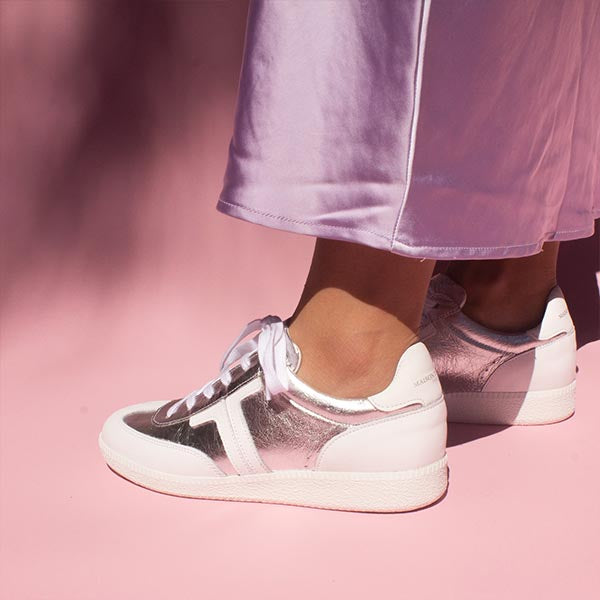 model wearing lilac satin skirt and silver leather sneaker sneakers in front of pink background