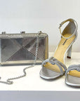 Silver metal hard shell clutch in art deco pattern with silver chain strap 