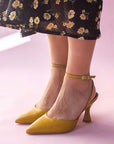 Alohas Cinderella marigold leather pumps on model wearing black and yellow floral skirt