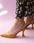 Alohas Cinderella marigold leather pumps on model wearing black and yellow floral skirt