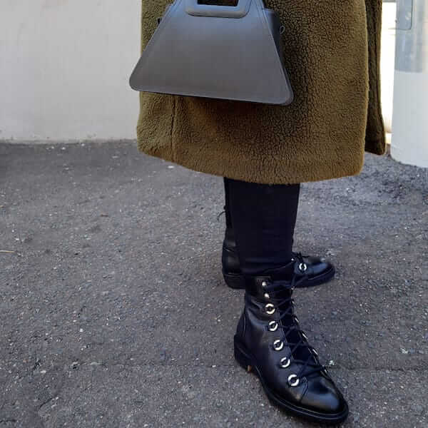 Black leather flat lace up combat boots by Billi Bi on model with winter coat