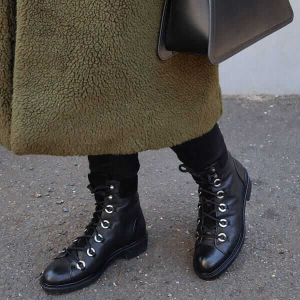 Black leather flat lace up combat boots by Billi Bi on model with winter coat, black jeans