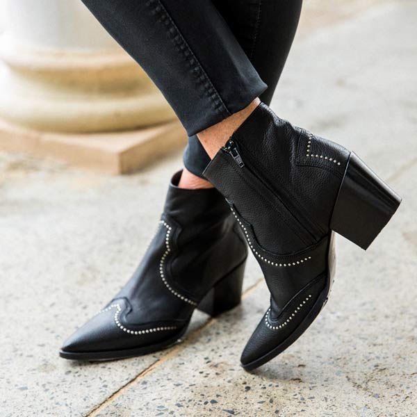 model in black jeans and Black leather, western heeled Billi Bi ankle boots with silver stud detail close up