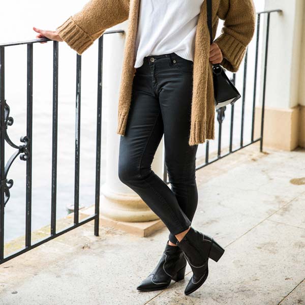model in black jeans, camel cardigan and Black leather, western heeled Billi Bi ankle boots with silver stud detail