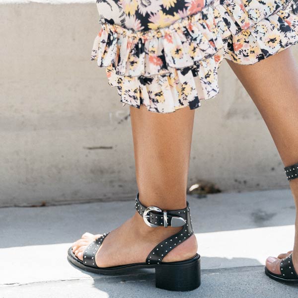 Low heel studded leather sandal on model wearing white floral dress