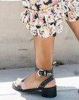 Low heel studded leather sandal on model wearing white floral dress