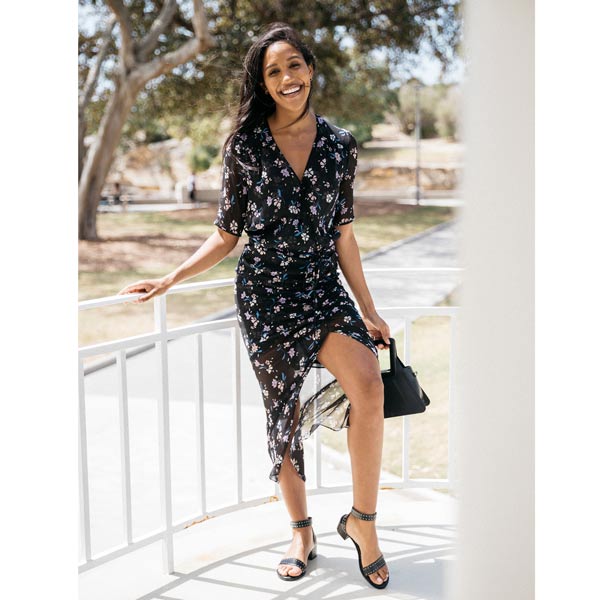 Low heel studded leather sandal worn by model wearing floral dress with black handbag