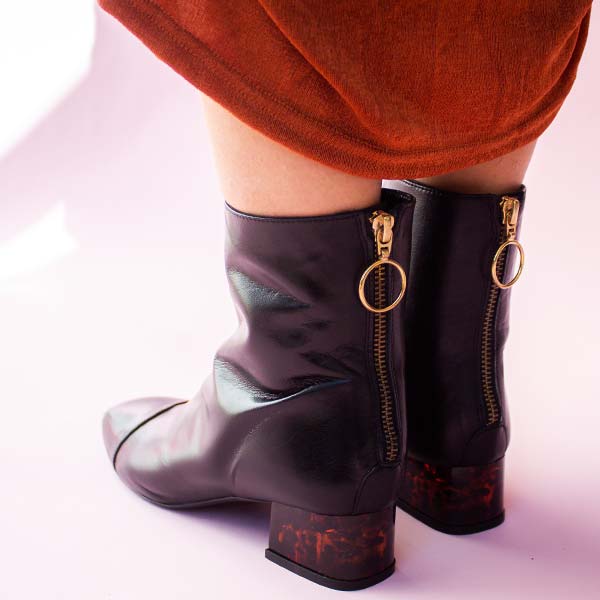 Mint&amp;Rose sol carey black ankle boot with low acrylic heel on model facing backwards in orange dress